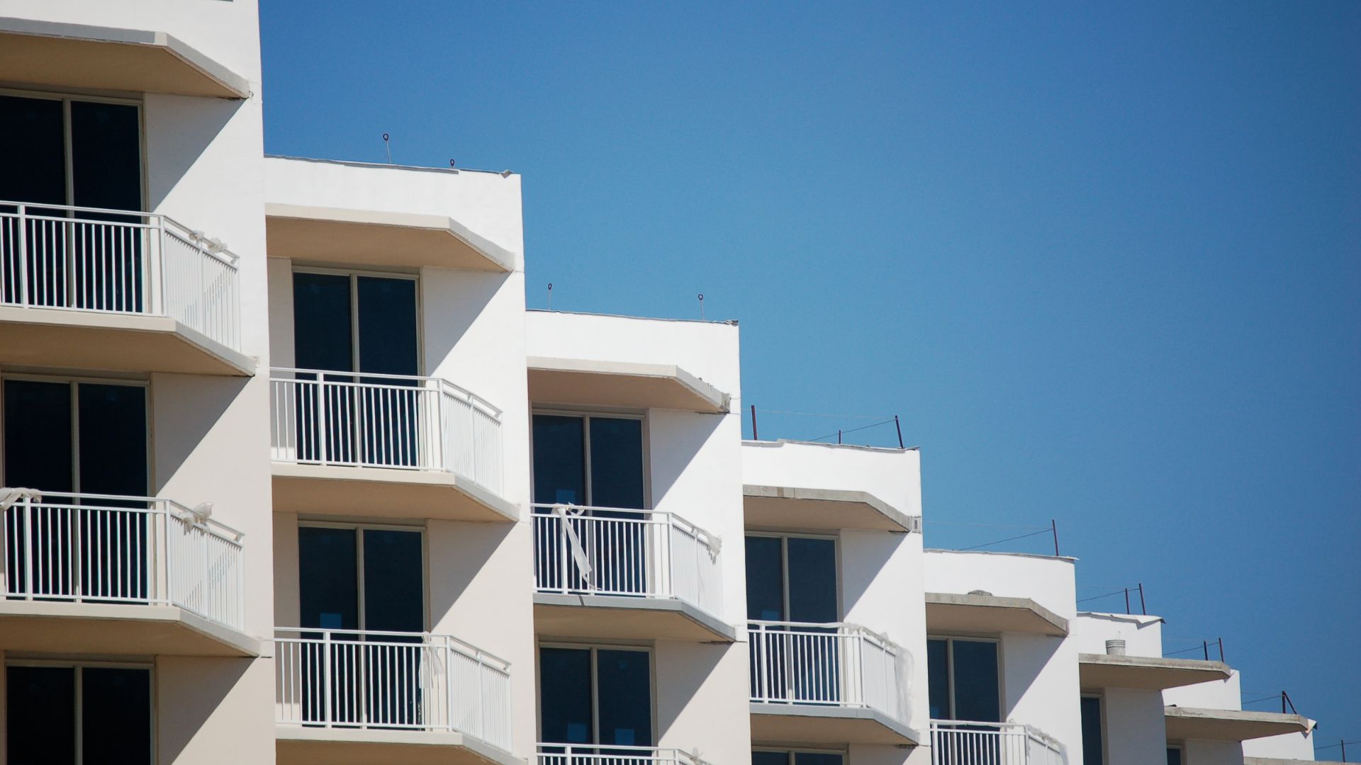 White oceanfront condo balconies under blue sky
